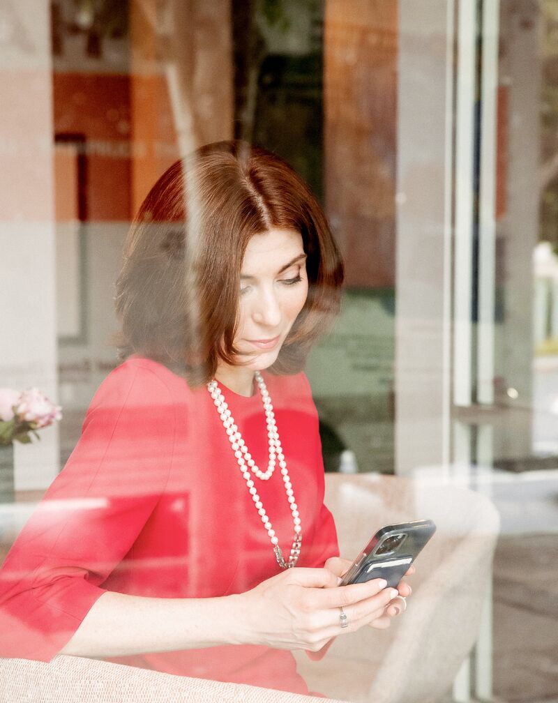 Svetlana Gershman looking at her phone through a reflective window